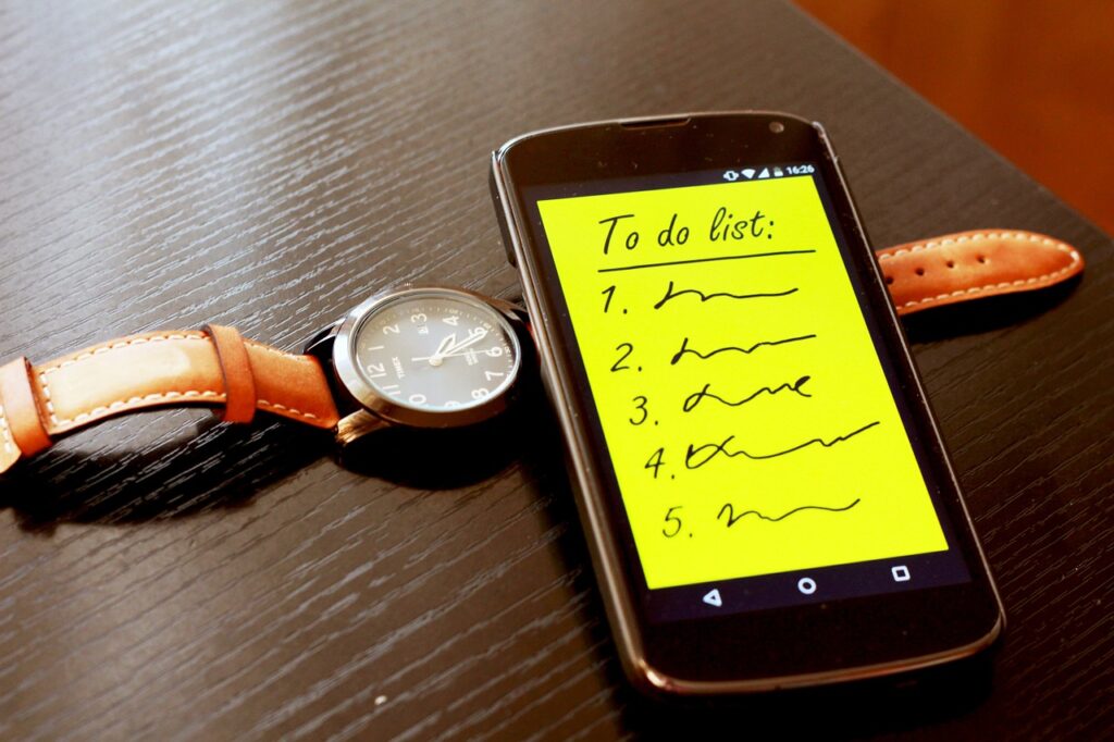 A watch and a phone on a desk. The phone shows a "To Do" list. 
