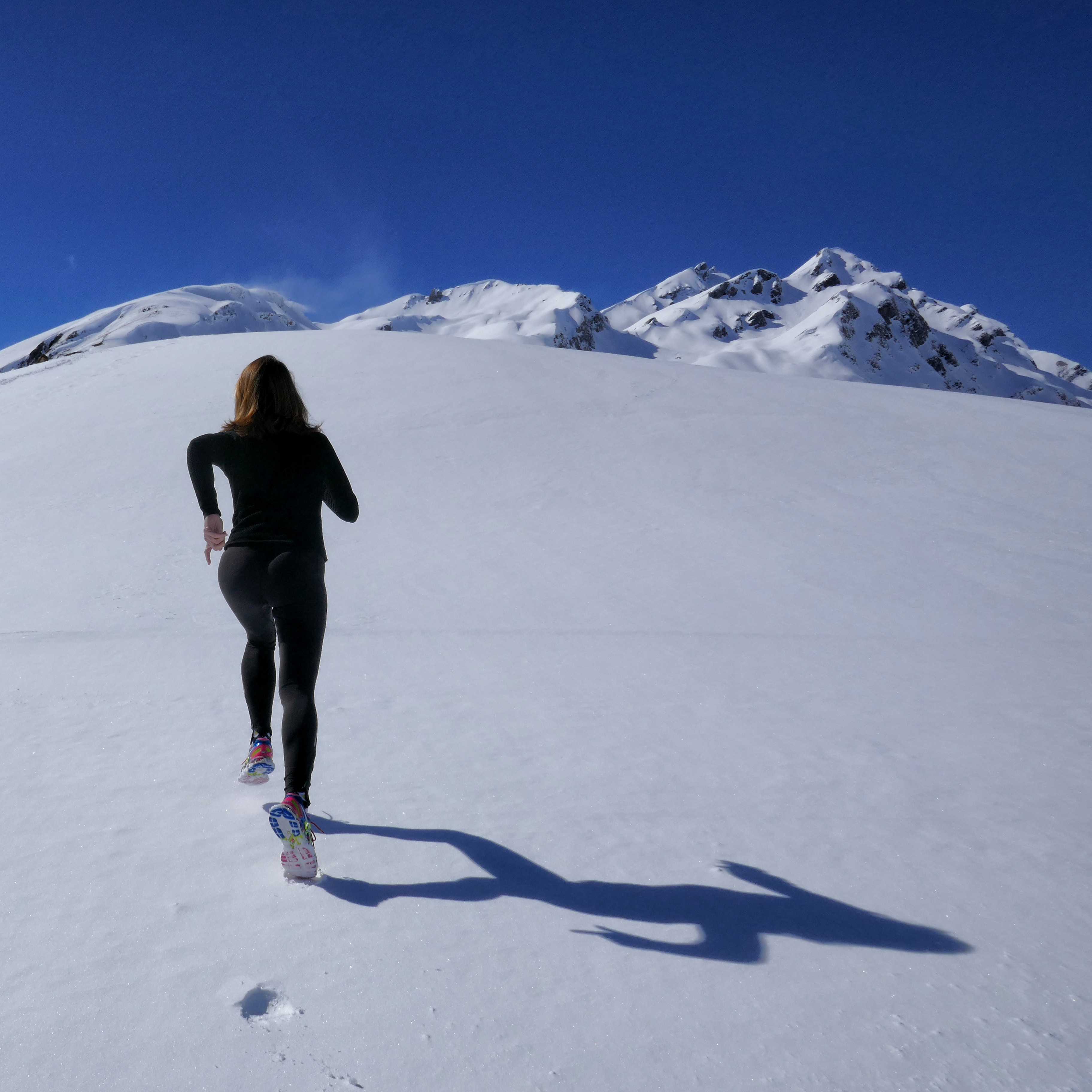woman running up snowy mountain